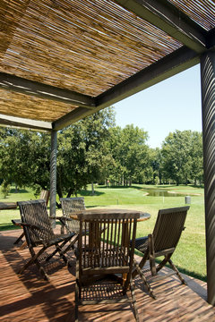 Terrace with wooden table and chairs under shelter of straw