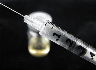 syringe and serum vial on black background