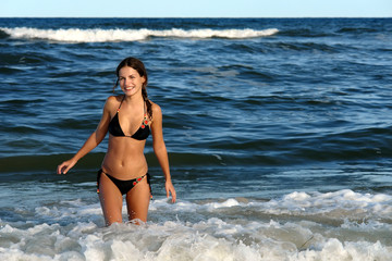 Beautiful young woman playing with waves on the ocean beach