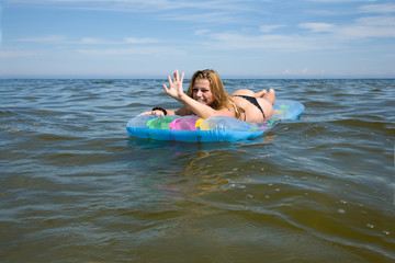 Beautiful girl swiming on air-mattress in sea