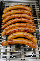 fried  pork sausages on a grill with gas