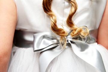 Twirled locks of golden hair against a flower-girl dress