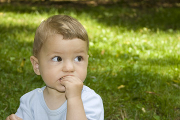 A cute small boy is eating in the nature.