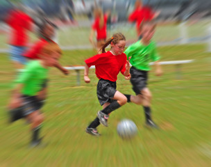 Young children running while playing soccer