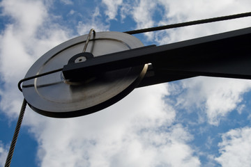 Pulley with a metal cable on fastening. Against the blue sky.
