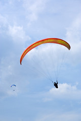 two paragliders silhouetted against summer sky