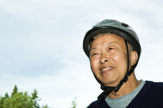 A Shot Of An Elderly Asian Man Wearing A Bike Helmet