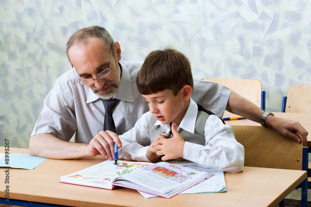 Wall mural teacher and schoolboy read alphabet. primary school.