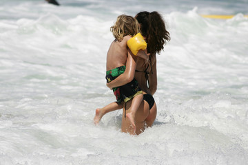belle femme dans les vagues avec son enfant dans les bras