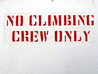 No Climbing Crew Only stenciled on white wall