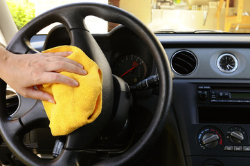 Woman's hand with microfiber cloth polishing steering wheel
