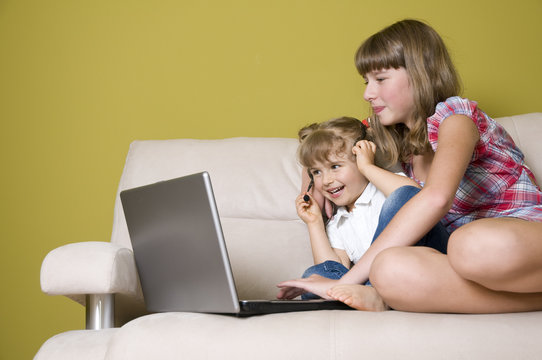 Sisters with laptops on sofa