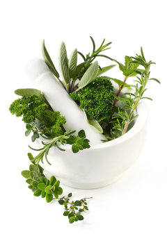 Fresh herbs in a white mortar with pestle.