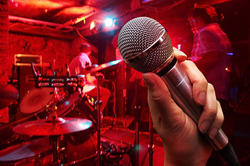 hand with microphone on a nightclub background