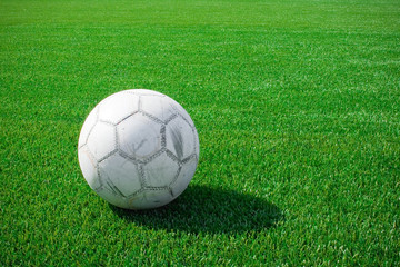 The football lays on a green grass