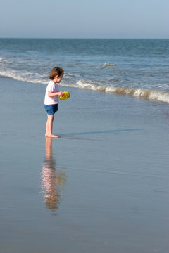 little girl with reflection playing on beach