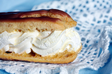 Chocolate eclair, on lace and pastel blue napkin.