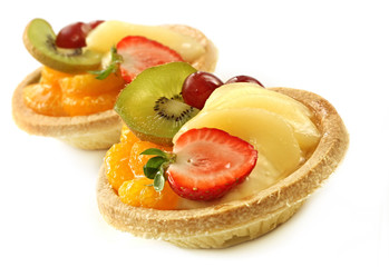 Small custard and glazed fruit tarts, isolated on white.