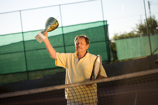 Active senior man in his 70s is posing on the tennis court