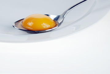 Broken egg on spoon, beauty of yellow