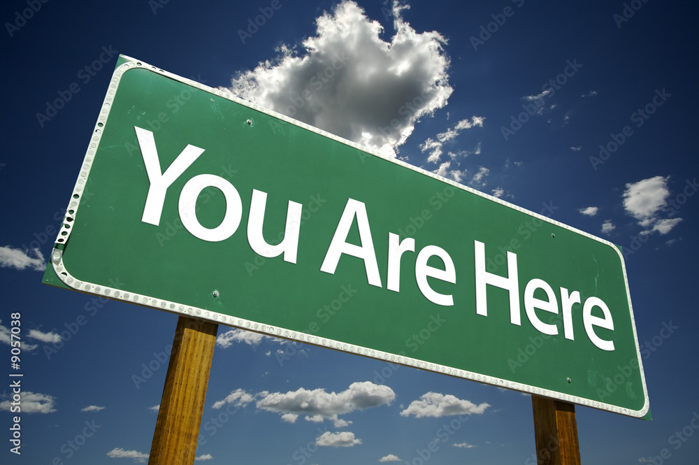 Wall mural You Are Here Road Sign with dramatic clouds and sky.