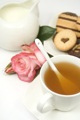 Cup of hot english tea served with milk and a rose flower
