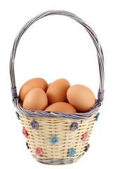 fresh whole brown eggs on wicker basket, white background