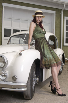 Beautiful woman leaning on a classic Jaguar car