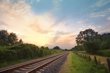Fotobehang Treinspoor pastel zonsonderganglandschap bij een spoorlijn