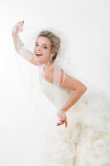 Photo of happy bride looking out of her veil and laughing