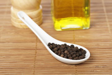 Peppercorns and oil with shadow in the background. Shallow DOF