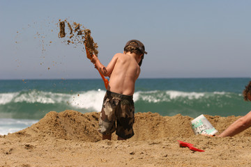 petit garçon entrain de jouer sur la plage avec une pelle