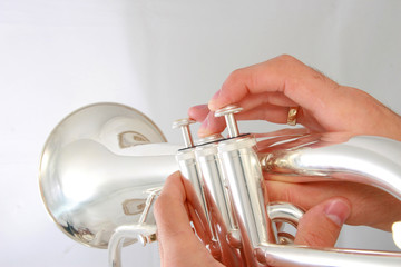 hand dolding a silver fluegelhorn on grey background