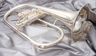 silver fluegelhorn with mouthpiece on a silver fabric