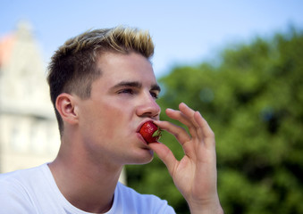 Young man eating strawberry