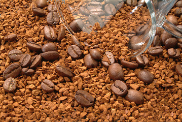Granules of instant coffee, coffee beans and a part of a glass