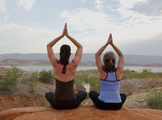 Two women doing yoga at sunset