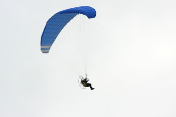 Motor powered paraglider isolated on gray sky
