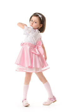 The lovely little girl posing in a beautiful pink dress.