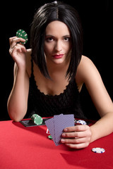Determined attractive brunette playing cards at a red poker