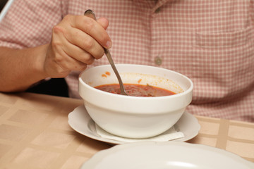 A man eats a red-beet soup in restaurant