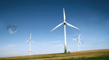 Wind turbines farm with full moon. Alternative energy source.
