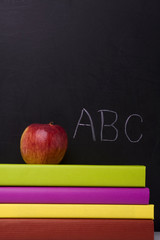 apple over a stack of books next to a chalkboard