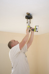 Electrician installing new light fixture and fan