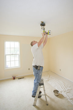 Electrician Installing New Light Fixture And Fan