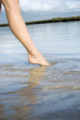 Woman dipping toe in the water.
