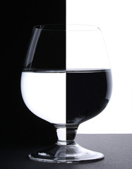 a glass with water in backlight on the black and white contrast
