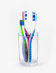 A family's toothbrushes in a glass container on white background
