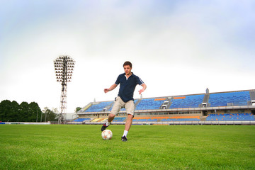 Fototapeta premium young guy playing football on stadium