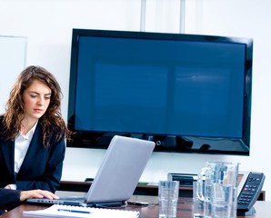 Young businesswoman sitting by meeting table at office
